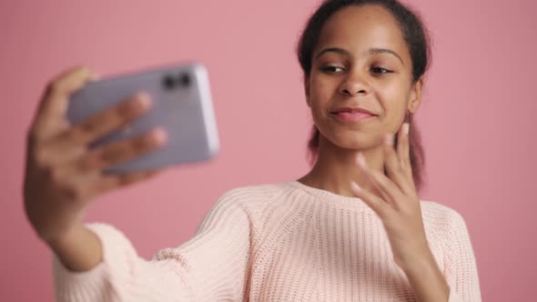 Positive African little girl making selfie by phone