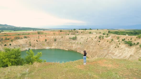 Lone Active Woman at the Edge of Abandoned Copper Mine Pit Taking Photos with Camera