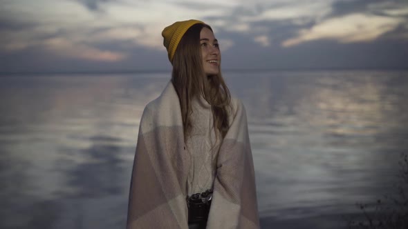 Portrait of Happy Young Caucasian Woman in Yellow Hat and Blanket Looking Around Admiring Beauty of