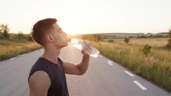 Young Sportsman Drinking Water From a Bottle and Looking Thoughtfully