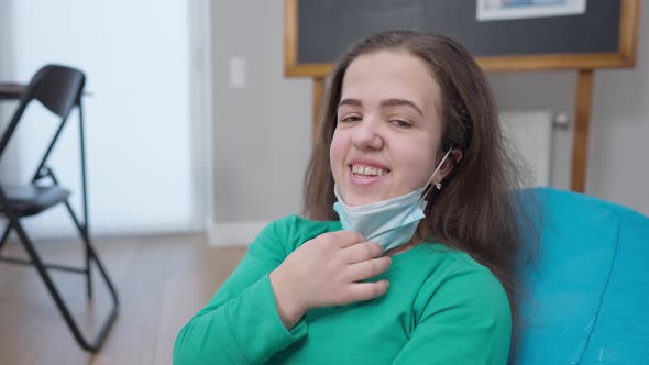 Positive Woman Taking Off Covid Face Mask Smiling Looking at Camera