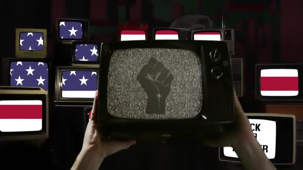 Hands rising Old TV Set with Clenched Fist on its Screen over American Flag.