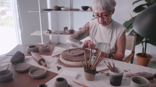 Asian elderly woman enjoying pottery work at home.