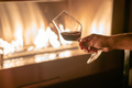 Hand holding a glass of red whine against fire pit - PhotoDune Item for Sale