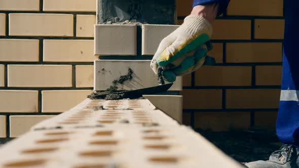 A Worker Laying Bricks on a Construction Site. alt