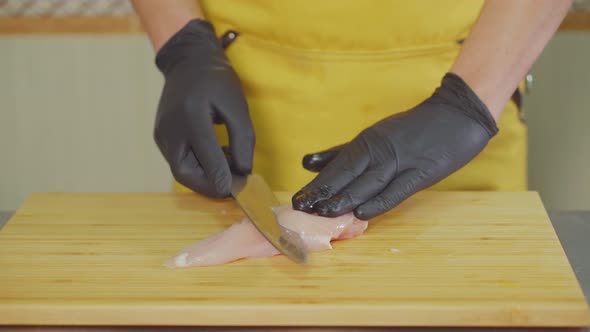 Cook Is Slicing Raw Chicken Fillet on Wooden Cutting Board, Close-up