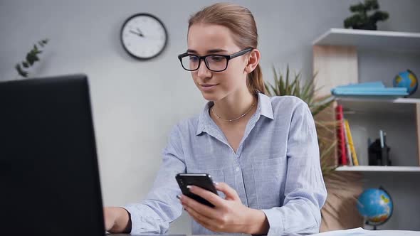 Smiling Woman in Glasses which Sitting in Modern Cabinet and Working Using Computer