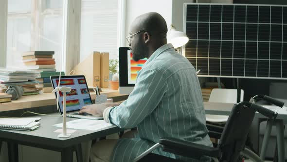 Man in Wheelchair Working on Renewable Energy Project at Home