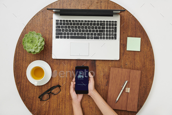 ding photos in My cloud while sitting at wooden table in front of laptop