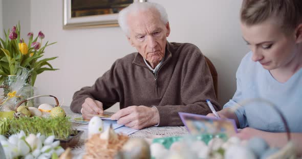 Happy Easter - Grandfather and Granddaughter Writing Easter Cards with Greetings.