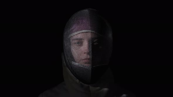 Portrait of Young Woman Fencer in Protective Helmet Turning and Looking at the Camera