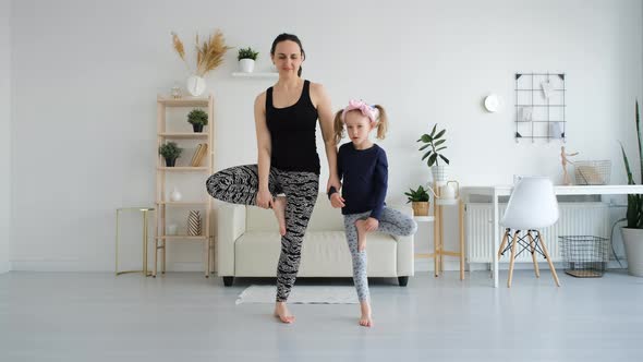 Mother with Little Daughter Doing Yoga Exercises