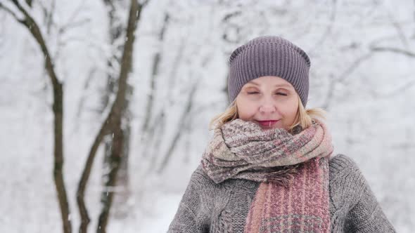 Portrait of a Woman in a Warm Sweater and Scarf, Stands Against the Background of a Snow-covered