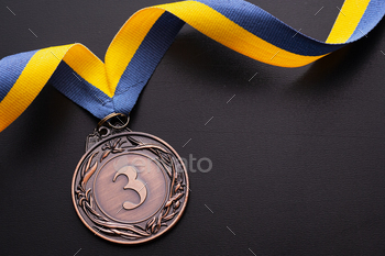 ion on a twirled blue and gold ribbon over a black background with copy space