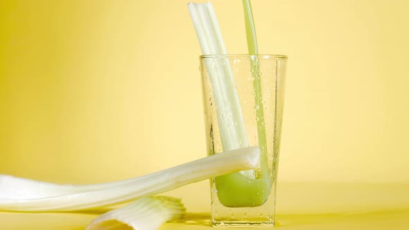 Delicious organic celery juice is poured in glass on a yellow colored background