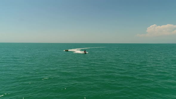 Tourists Ride on the Sea on a Large Inflatable Circle Using a Water Scooter