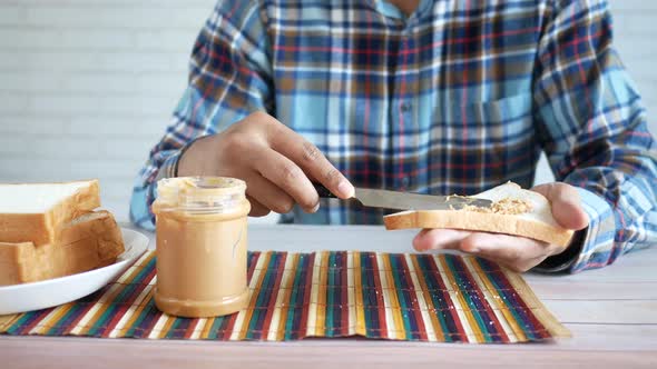 Young Man Eating Peanut Butter and Bead While Sited