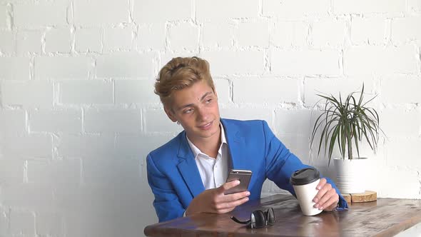 Young Man Using Mobile Phone at Cozy Coffee Shop.