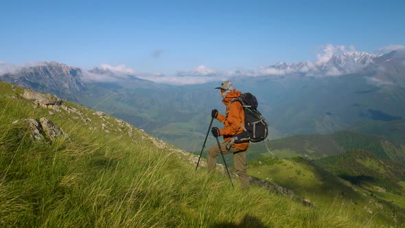 Young Caucasian Woman Tourist with a Backpack and Trekking Poles in Caps and Sunglasses on a Summer