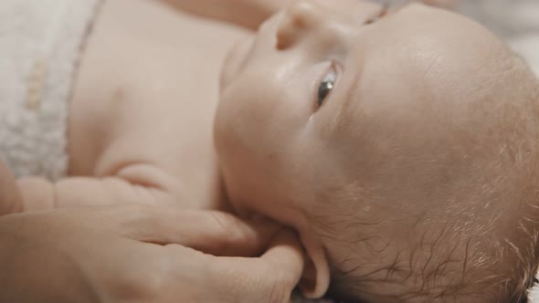 A Little Baby Lying in Bed and His Parent Cleaning His Ears with Q-tips