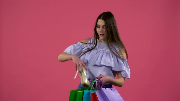 Girl Gets a Shoe From the Bag and Is Happy. Pink Background