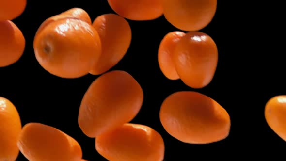 Closeup of Ripe Delicious Orange Kumqats Falling Down on the Black Background