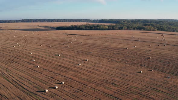 Beautiful morning flight over haystacks. The field is covered with hay.