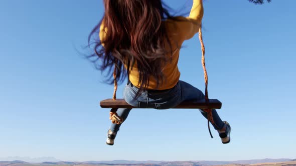 View of a woman in the summer on a swing