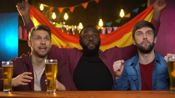 Cheerful Multiracial Male Fans Cheering for Spanish Sports Team, Waving Flag