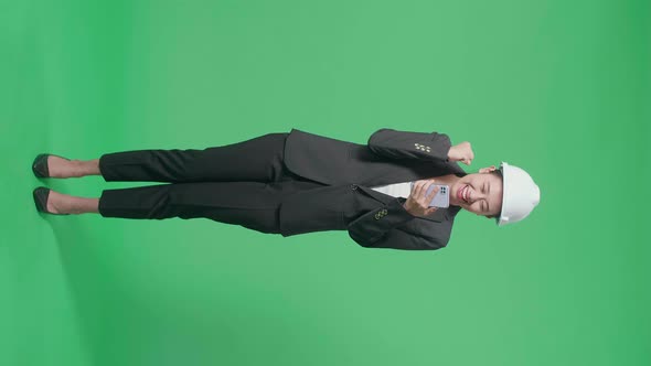 Full Body Of Asian Female Engineer Celebrating While Using Smartphone In The Green Screen Studio