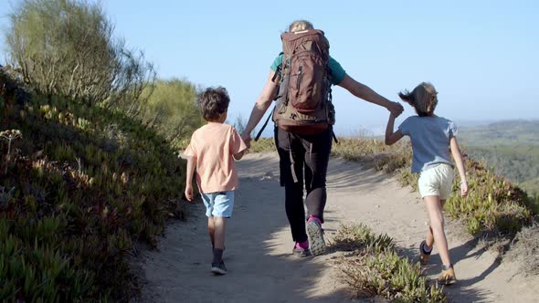 Kids and Mom Wearing Backpack Walking on Path in Mountains