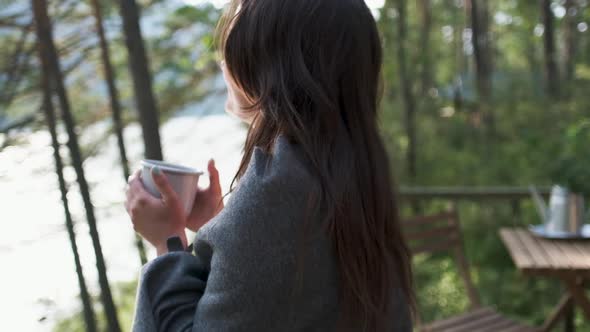 Beautiful Girl Wrapped in a Plaid on a Balcony in a Mountain House Enjoying a Cup of Tea. Attractive