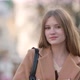 Attractive young lady in warm coat looking to camera on city street background. - VideoHive Item for Sale