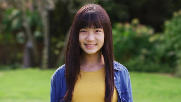 Portrait of happy asian teenage girl looking to camera smiling and laughing in garden