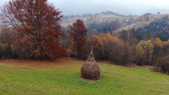 Aerial Drone Footage View: Flight around haycock in autumn mountain fields.