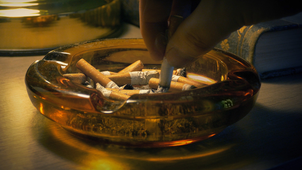 Man Puts Out Cigarette In Ash Tray