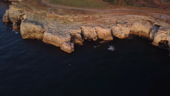 Drone top down aerial view of waves splash against rocky seashore, background. Flight over high clif