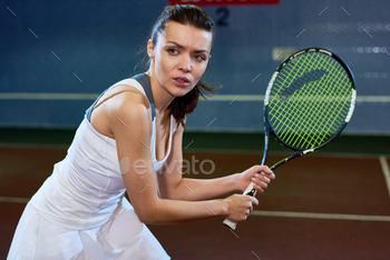 g tennis in indoor court, forcefully hitting ball with racket