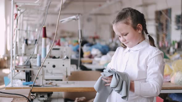 Little Girl Standing in the Factory with a Thread