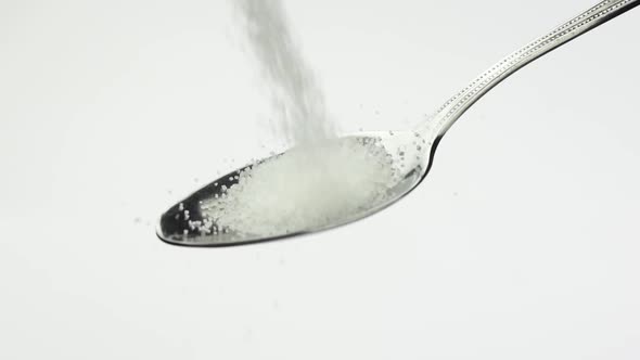 White Granulated Sugar Fall Teaspoon on a White Background in Slow Motion