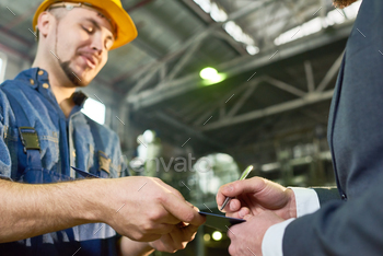 ument on clipboard while visiting modern plant for investment inspection