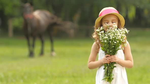 Little Girl with Wild Flowers in Their Hands Sniffs Them. Slow Motion