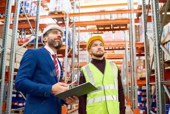 pboard talking to worker wearing hardhat and reflective jacket while discussing stock inventory