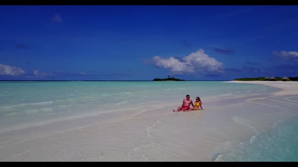 Man and woman relax on perfect coastline beach holiday by turquoise ocean and white sandy background