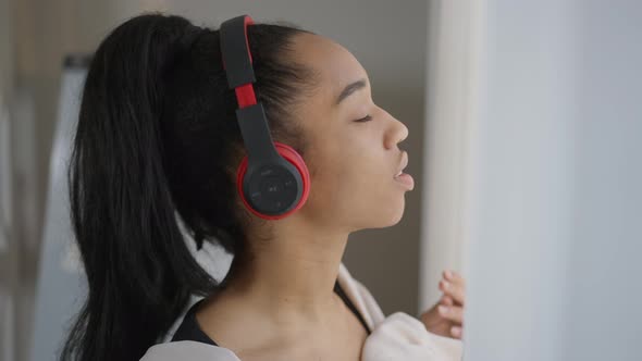 Closeup of Happy African American Woman in Headphones Enjoying Music Dancing Having Break in Home