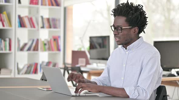 African Man with Neck Pain Working on Laptop