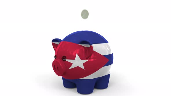 Coins Fall Into Piggy Bank Painted with Flag of Cuba