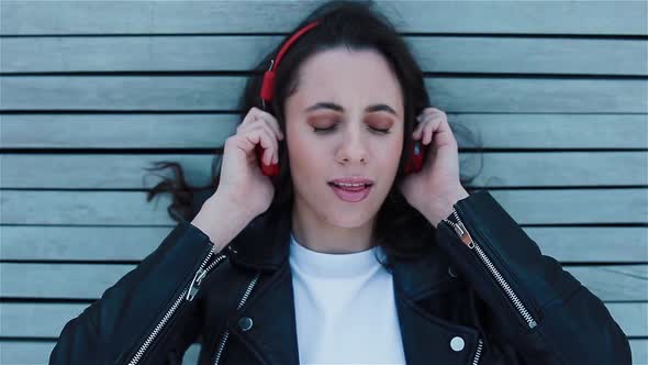 Young Woman Listening To Music in Headphones Laying on the Bench