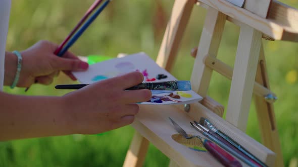 Workshop of Artist Outdoors in Park Palette with Colors on Easel Woman is Drawing