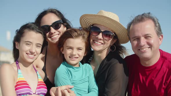 Front View of Happy Family Standing on Beach and Hugging